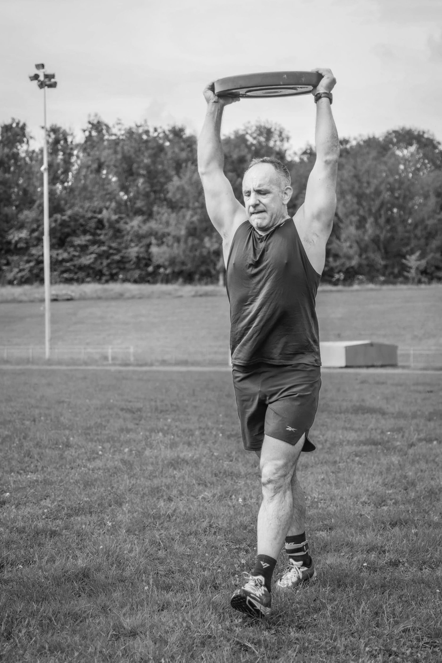 Athlète portant une plaque de poids au-dessus de la tête lors de l'exercice « Overhead Carry Labour »
