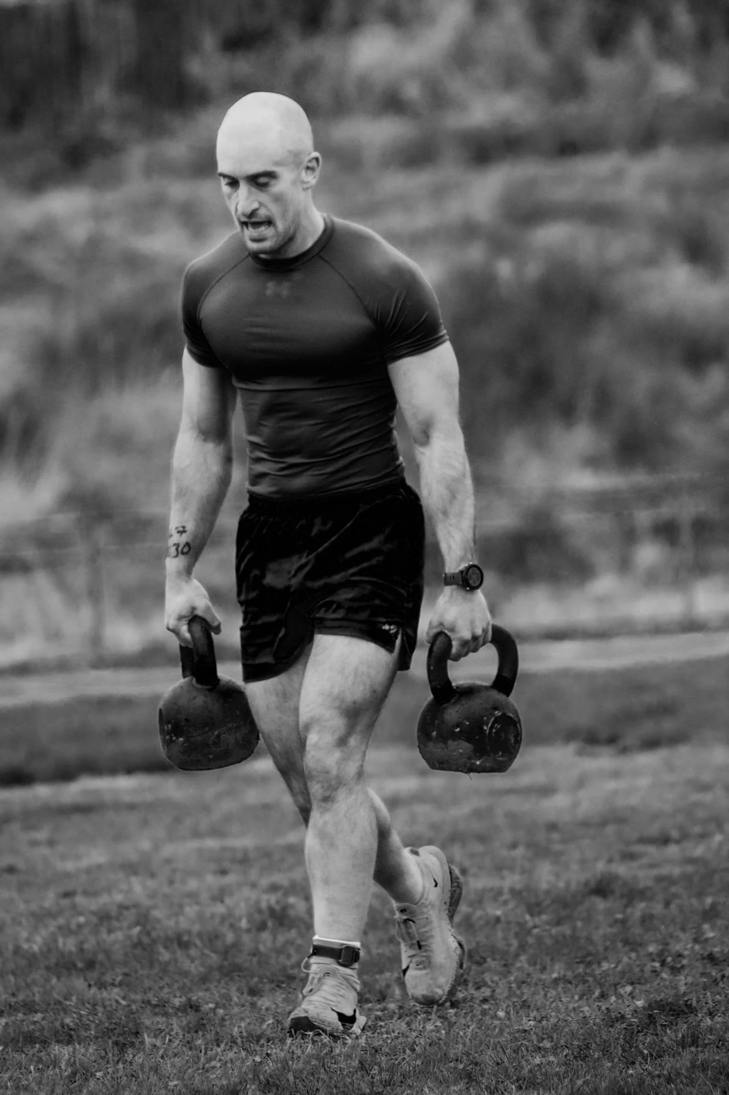 Un athlète transportant deux kettlebells sur la piste de 30 mètres lors de l'épreuve « Farmers Carry »